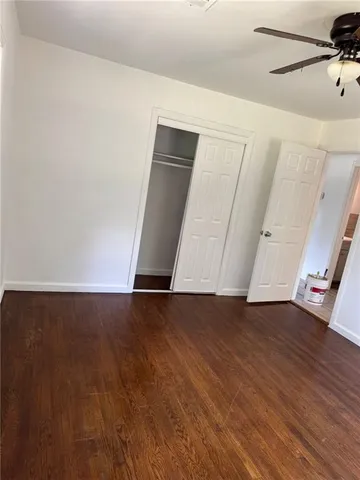 an empty room with wooden floor chandelier fan and windows