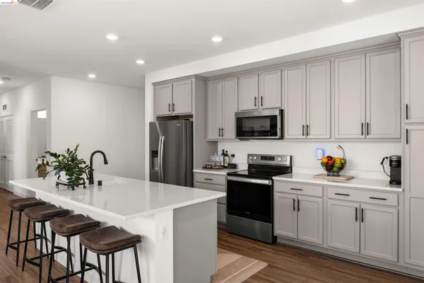 a kitchen with stainless steel appliances a sink a stove a refrigerator cabinets and a center island