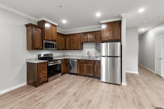 a kitchen with stainless steel appliances granite countertop a refrigerator a stove top oven a sink and dishwasher with wooden floor