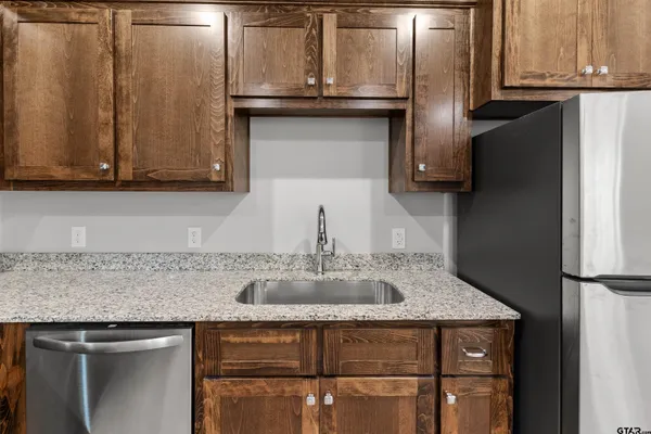 a kitchen with granite countertop a sink cabinets and stainless steel appliances
