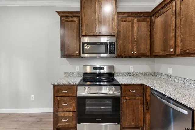 a kitchen with granite countertop a stove top oven microwave and cabinets