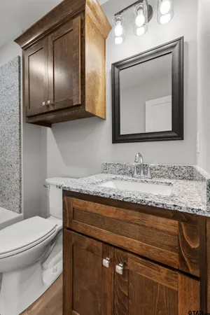 a bathroom with a granite countertop toilet sink and mirror