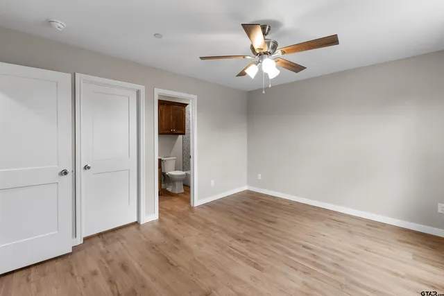 an empty room with wooden floor fan and windows