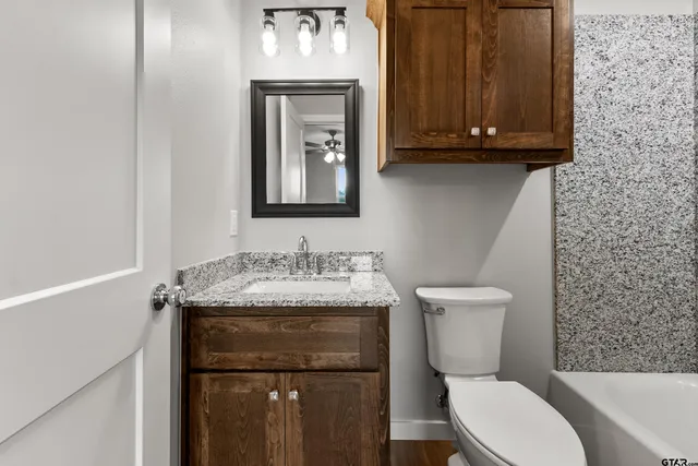 a bathroom with a granite countertop toilet and a sink