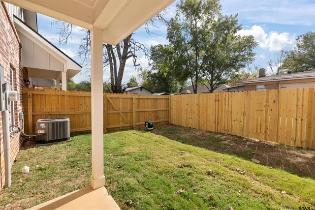 a view of backyard path with wooden fence