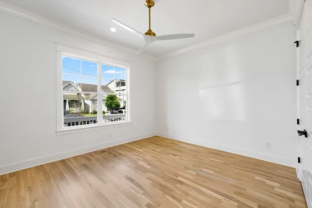 a view of an empty room with window and wooden floor