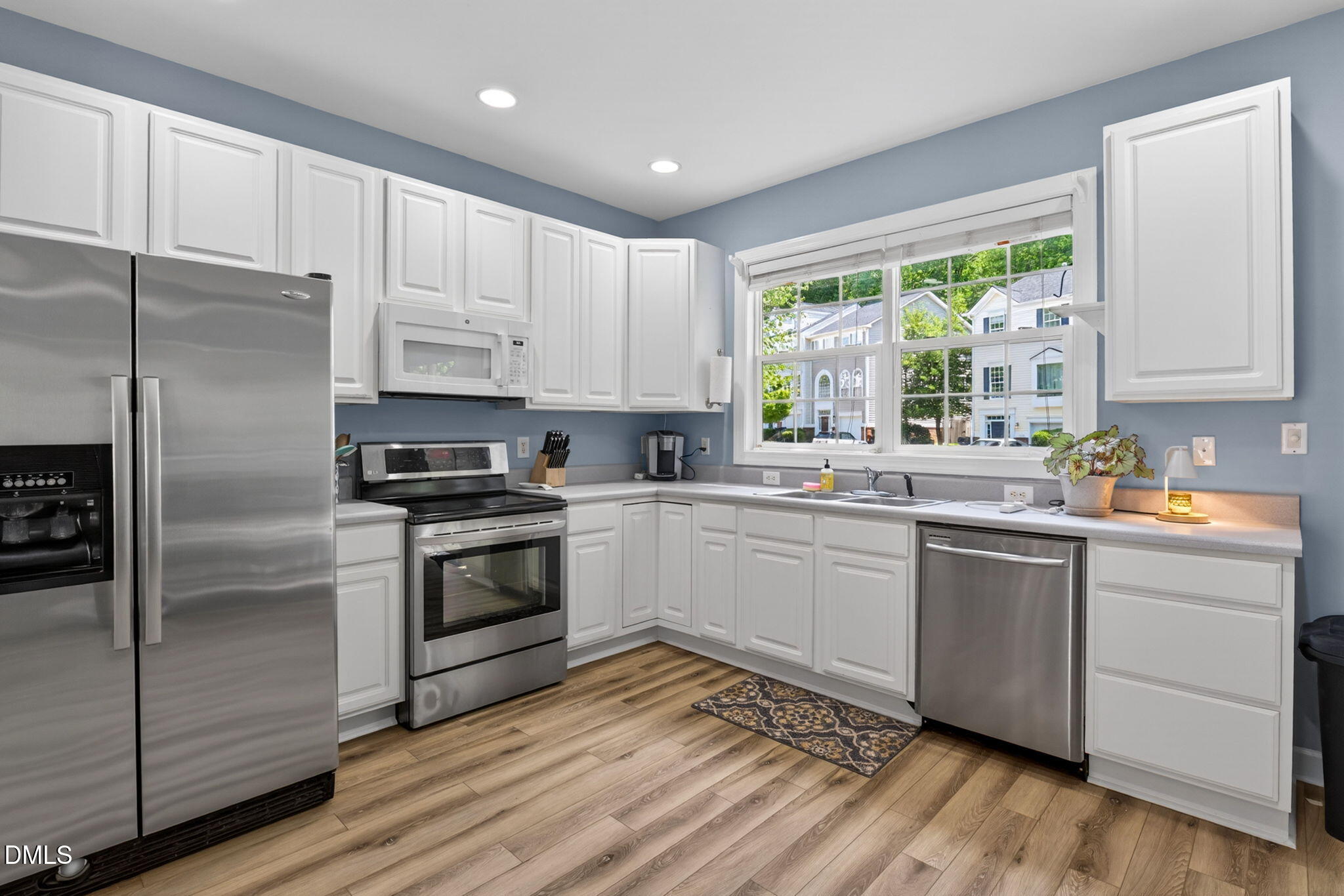 5500 Vista View Court Raleigh, NC 27612 - Photo 11 of 38 a kitchen with a refrigerator wooden floor a sink a window and cabinets
