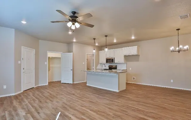 an empty room with wooden floor and a kitchen