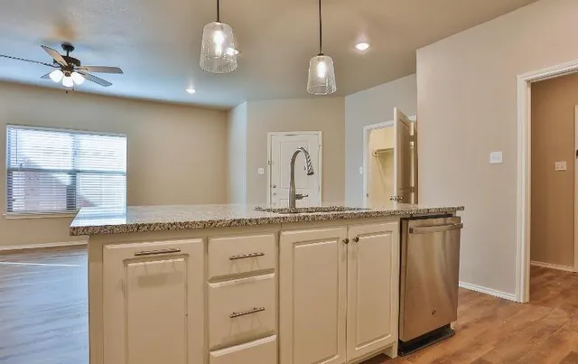 a kitchen with stainless steel appliances granite countertop white cabinets and a stove top oven
