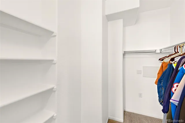 a view of walk in closet with clothes and shoes