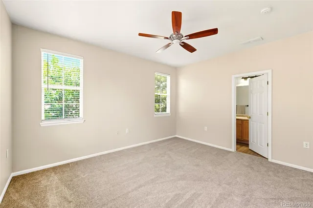 a view of a livingroom with a ceiling fan & windows