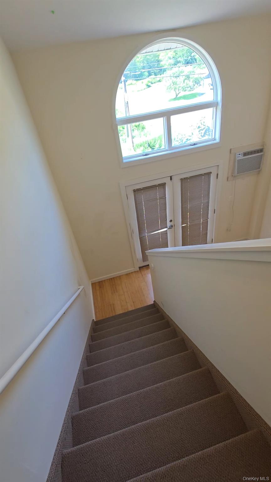 231 Reynolds Road, Unit 9 Fallsburg, NY 12759 - Photo 10 of 15 Stairway with wood finished floors, a wall mounted AC, and french doors