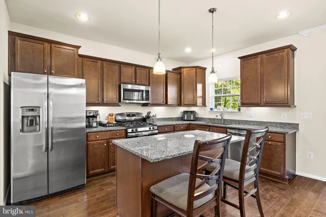 a kitchen with kitchen island granite countertop a center island a sink cabinets and stainless steel appliances