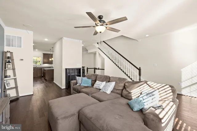 a living room with furniture and kitchen view with wooden floor