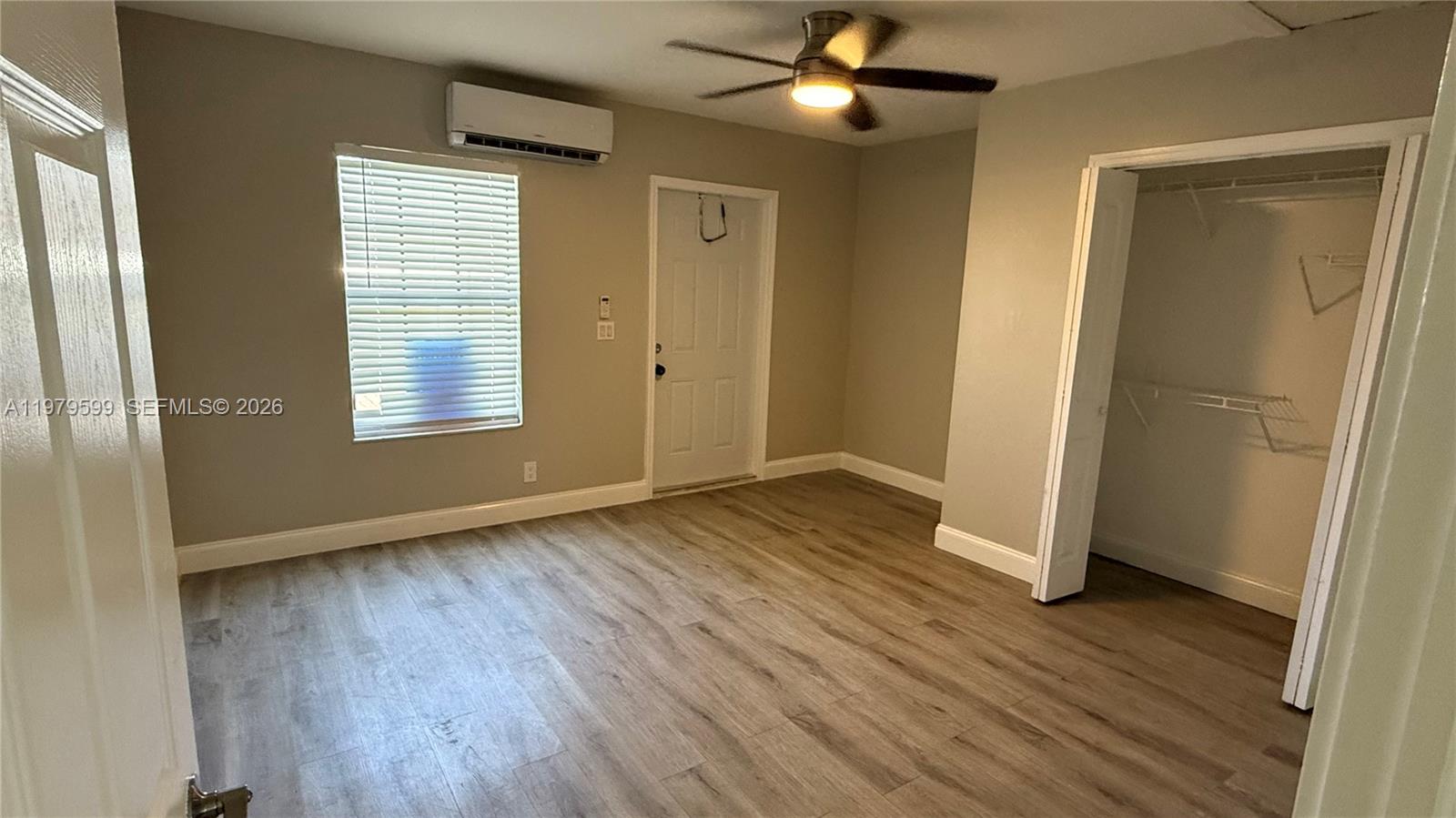 220 Northwest 12th Street, Unit 14 Pompano Beach, FL 33060 - Photo 11 of 19 an empty room with wooden floor a ceiling fan and windows