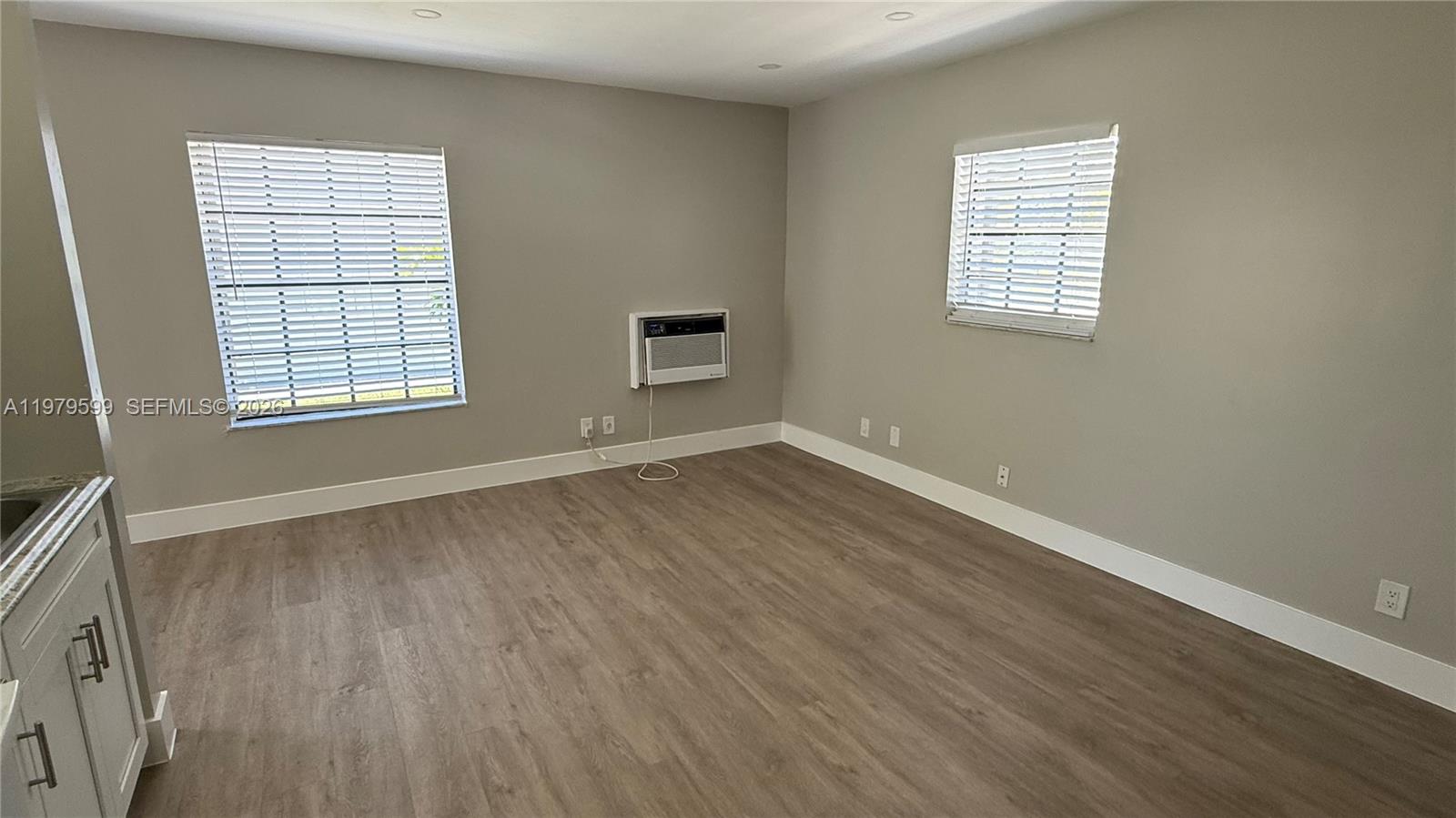 220 Northwest 12th Street, Unit 14 Pompano Beach, FL 33060 - Photo 10 of 19 a view of an empty room with wooden floor and a window