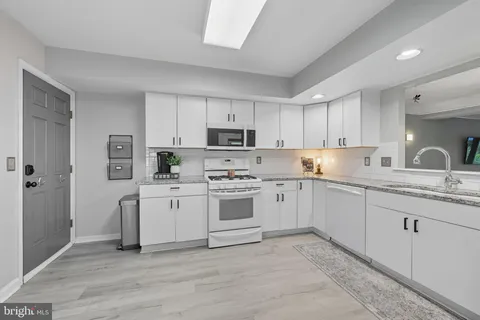 a kitchen with granite countertop white cabinets and white appliances
