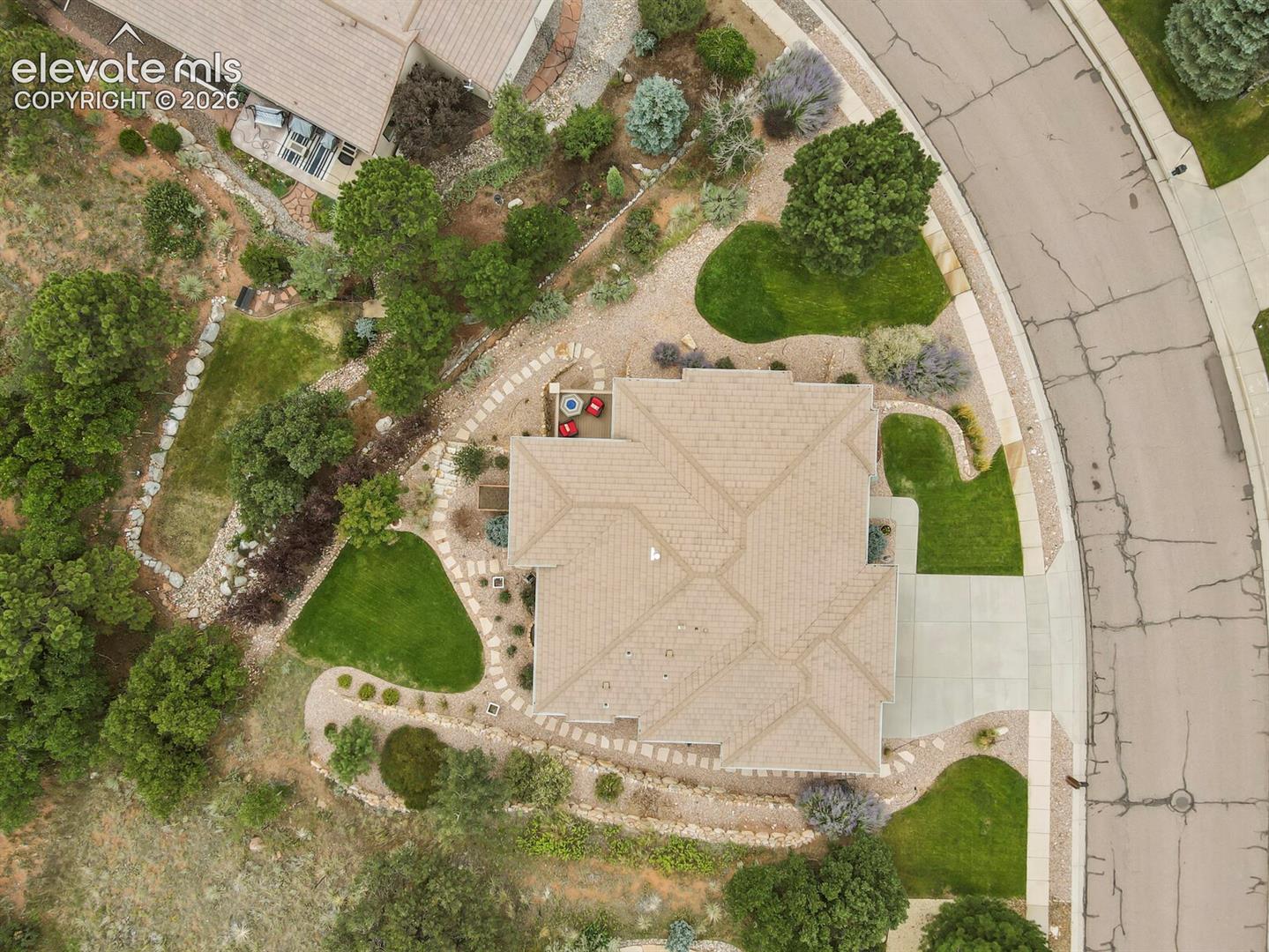 5545 Wilson Road Colorado Springs, CO 80919 - Photo 46 of 48 Paved driveway, concrete walkways, tiled roof, landscaped grounds, and stone retaining walls