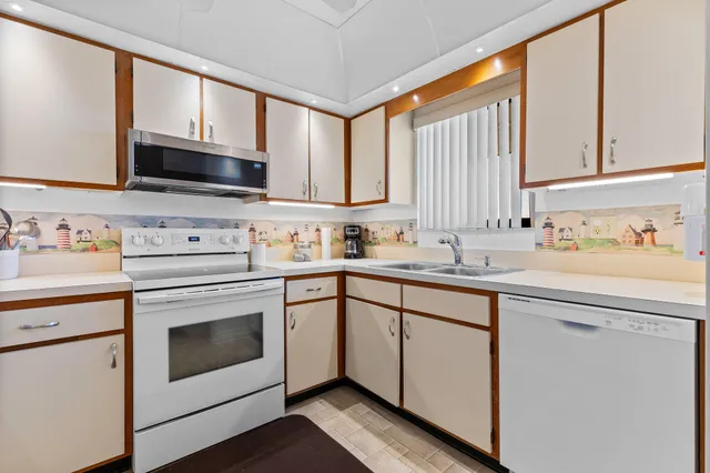 a kitchen with stainless steel appliances white cabinets sink and a window