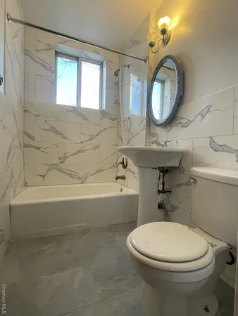 a bathroom with a toilet a sink a mirror and bathtub