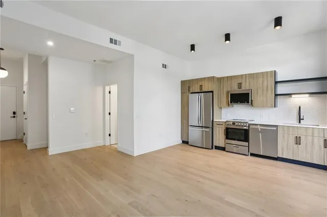 a view of a kitchen with stainless steel appliances a refrigerator and a stove top oven