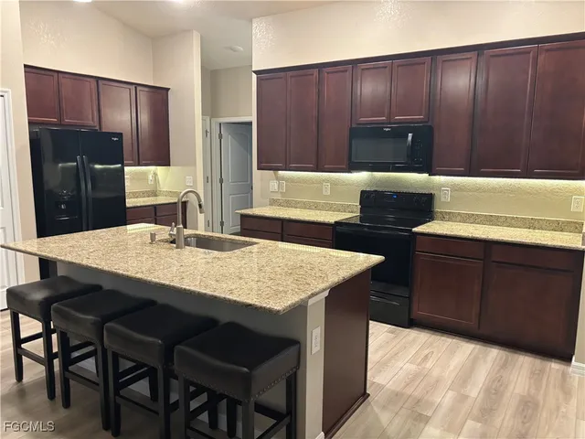 a living room with stainless steel appliances furniture a rug and a kitchen view