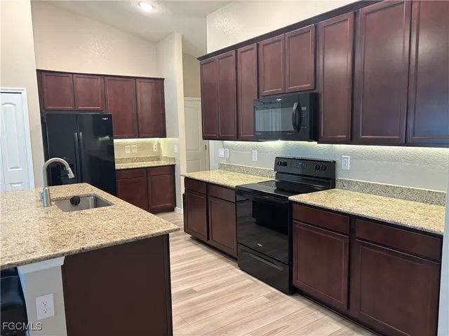 a kitchen with kitchen island granite countertop a sink stove and refrigerator