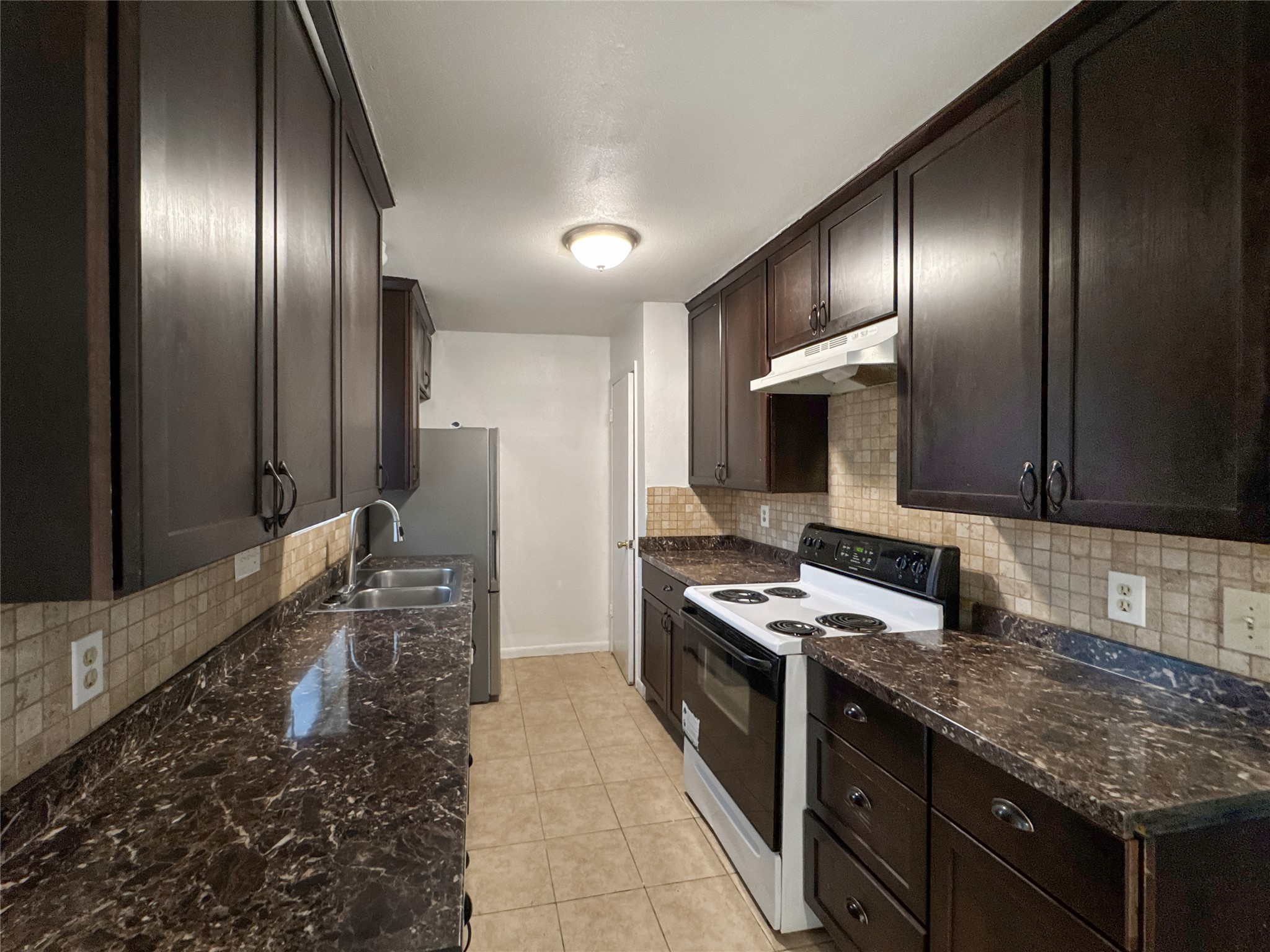 2017 Greenbrook Parkway, Unit B Austin, TX 78723 - Photo 6 of 14 Kitchen featuring electric stove, dark brown cabinetry, decorative backsplash, and under cabinet range hood
