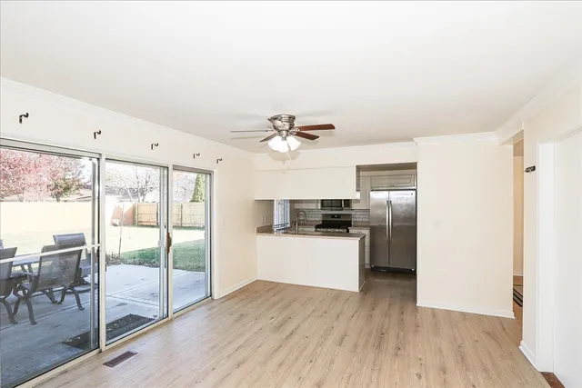 a kitchen with stainless steel appliances a refrigerator a sink dishwasher a stove and a dining table with wooden floors