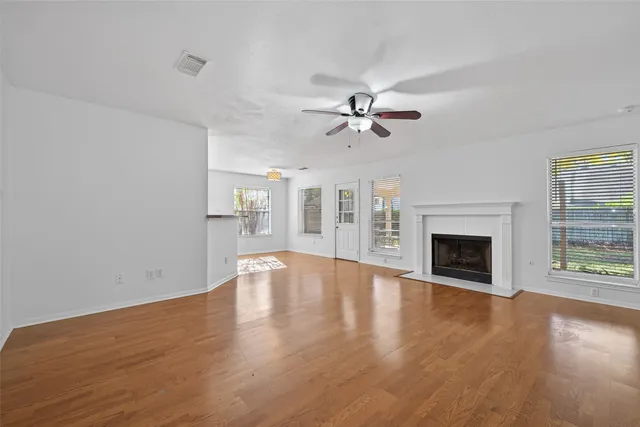 a view of an empty room with wooden floor fireplace and a window