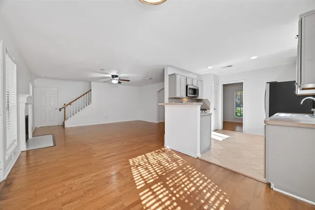 a view of a kitchen with a sink a refrigerator and wooden floor