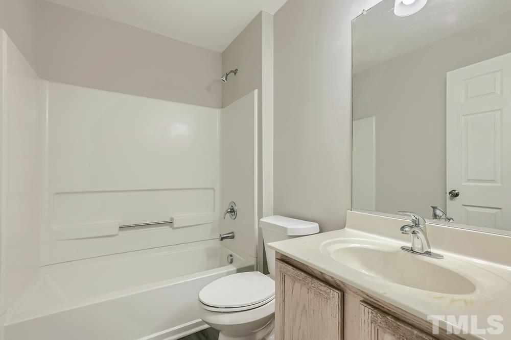 8610 Neuse Landing Lane, Unit 109 Raleigh, NC 27616 - Photo 19 of 28 a bathroom with a granite countertop toilet a sink and a bathtub