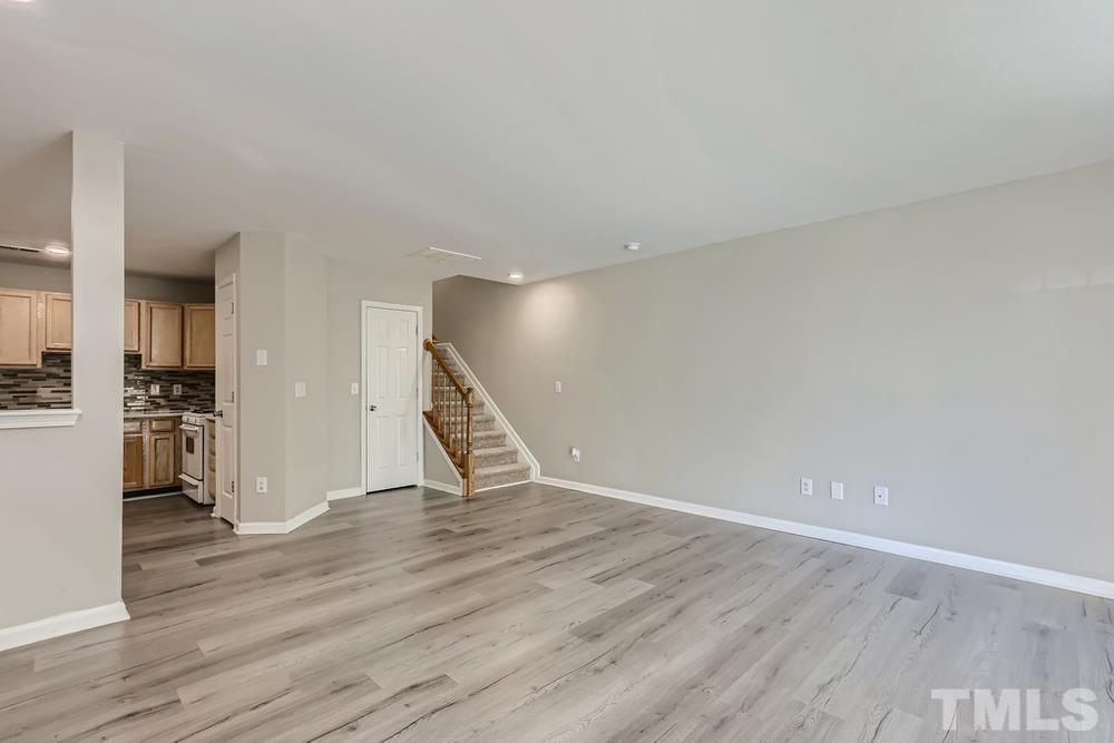 8610 Neuse Landing Lane, Unit 109 Raleigh, NC 27616 - Photo 4 of 28 a view of an empty room with wooden floor and a refrigerator