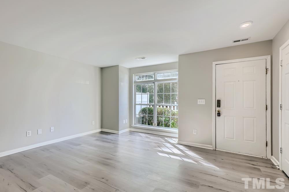 8610 Neuse Landing Lane, Unit 109 Raleigh, NC 27616 - Photo 5 of 28 a view of an empty room with wooden floor and a window