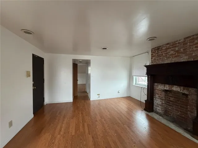 a view of empty room with wooden floor and fireplace