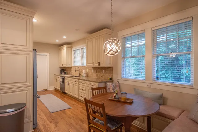 a kitchen with stainless steel appliances granite countertop a stove a refrigerator and a dining table with wooden cabinet