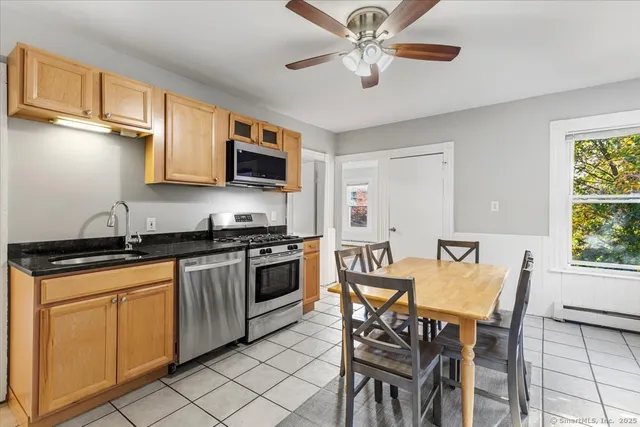 a view of a kitchen with granite countertop a stove top oven a sink a dining table and chairs
