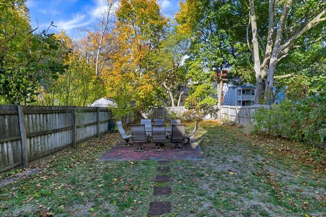 a view of a backyard with table and chairs and a large tree