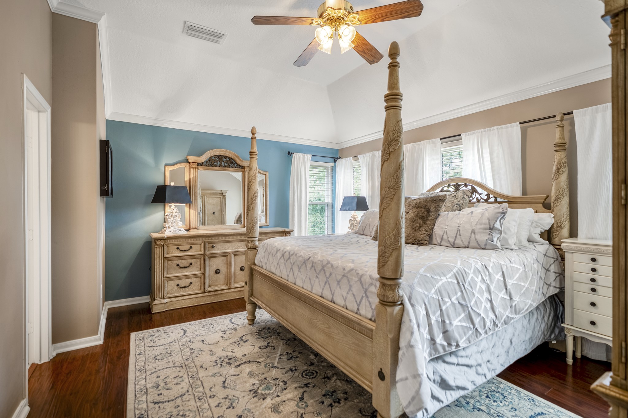 20235 Eden Pines Spring, TX 77379 - Photo 19 of 50 Step through from the game room into a primary bedroom that feels bright and open, with soaring vaulted ceilings, LVP flooring & natural light pouring in from multiple windows. The room has plenty of space to unwind at the end of the day, while the doorway to the left leads into the primary bath.