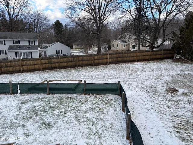 an empty room with wooden floor fireplace and windows