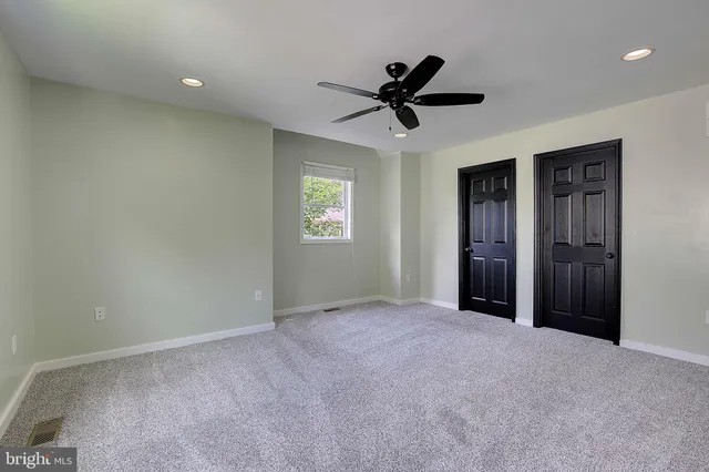 a view of a livingroom with a ceiling fan & windows