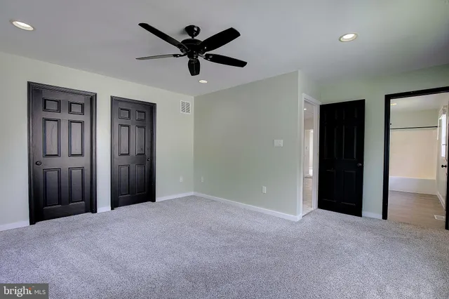 an empty room with closet and ceiling fan