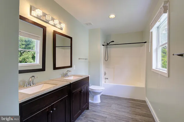 a bathroom with double vanity sinks a toilet a mirror and shower