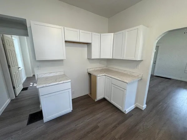 a kitchen with white cabinets and wooden floor