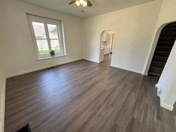 a view of an empty room with wooden floor and a window
