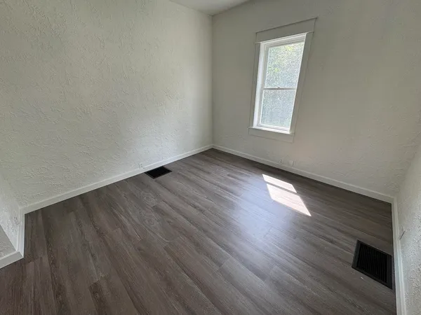 an empty room with wooden floor and a window