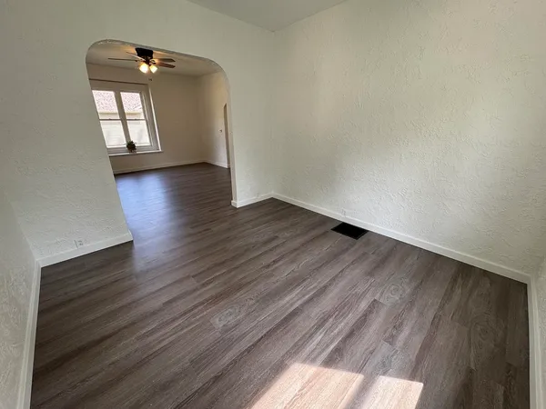 a view of empty room with wooden floor and fan
