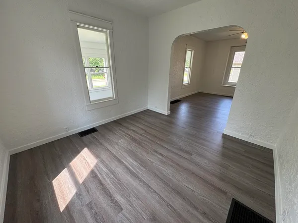 a view of an empty room with wooden floor and a window