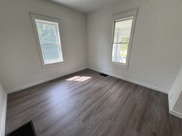 an empty room with wooden floor and windows