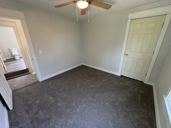an empty room with windows and fan